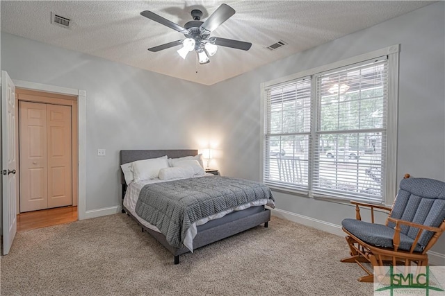 carpeted bedroom featuring baseboards, visible vents, and a textured ceiling