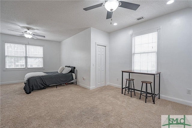 bedroom featuring a textured ceiling, carpet flooring, visible vents, baseboards, and a closet