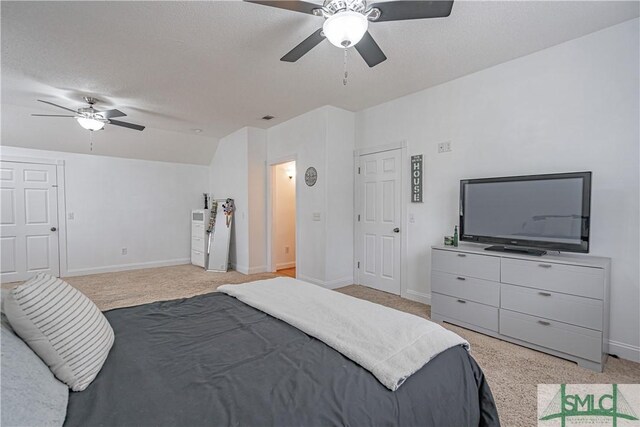 bedroom featuring light carpet, vaulted ceiling, a textured ceiling, and ceiling fan