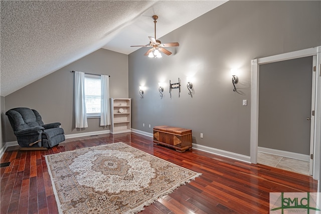 sitting room with a textured ceiling, vaulted ceiling, dark hardwood / wood-style floors, and ceiling fan