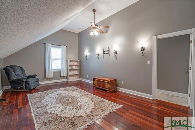 living area featuring a textured ceiling, baseboards, vaulted ceiling, and dark wood-style flooring