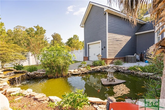 view of property exterior with a garden pond, brick siding, fence, and an attached garage