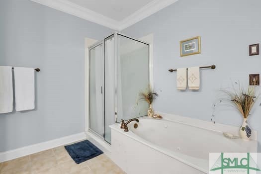 bathroom with tile patterned flooring, baseboards, ornamental molding, a shower stall, and a bath