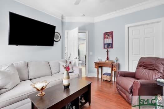 living area with a ceiling fan, crown molding, and wood finished floors