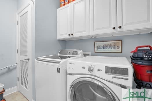 laundry area with cabinet space, baseboards, and washer and clothes dryer