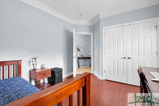 bedroom featuring baseboards, a closet, wood finished floors, and crown molding