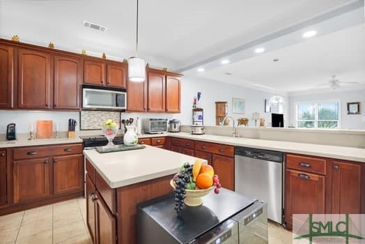 kitchen featuring appliances with stainless steel finishes, a peninsula, light tile patterned flooring, light countertops, and recessed lighting