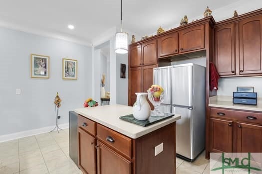 kitchen with light tile patterned floors, light countertops, freestanding refrigerator, a center island, and decorative light fixtures