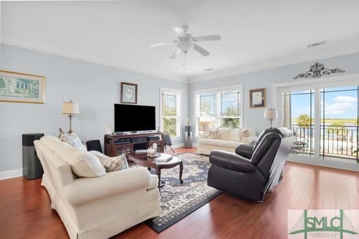 living area with a ceiling fan, plenty of natural light, baseboards, and wood finished floors