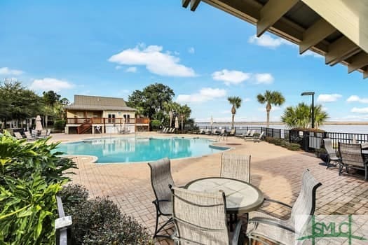 community pool with outdoor dining space, a patio area, and fence