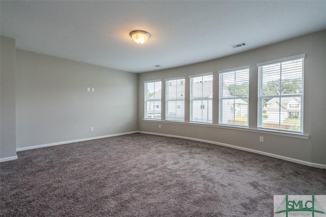 unfurnished room with carpet floors, baseboards, visible vents, and a textured ceiling