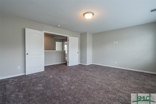 unfurnished bedroom with visible vents, dark carpet, and baseboards