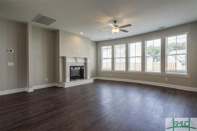 unfurnished living room featuring baseboards, visible vents, a ceiling fan, a glass covered fireplace, and dark wood-style floors