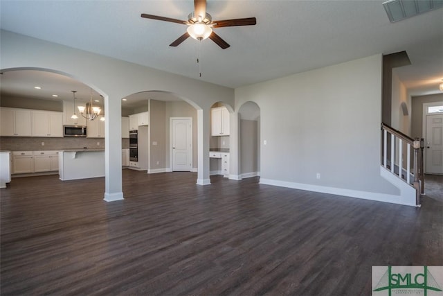 unfurnished living room featuring dark wood-type flooring, stairway, visible vents, and baseboards