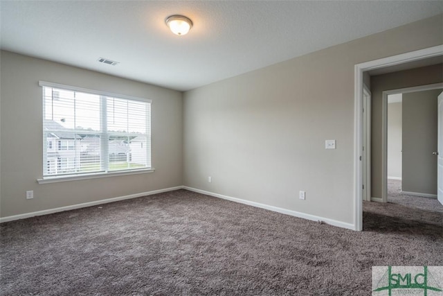 carpeted empty room featuring visible vents and baseboards