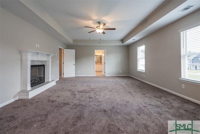 unfurnished living room featuring plenty of natural light, visible vents, baseboards, and a high end fireplace