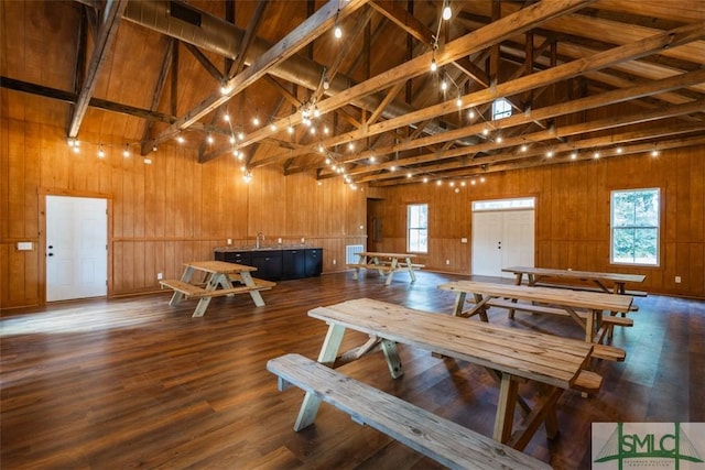 dining area featuring wood walls, high vaulted ceiling, and wood finished floors