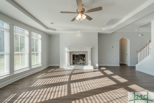 unfurnished living room with plenty of natural light, ceiling fan, and dark wood-type flooring