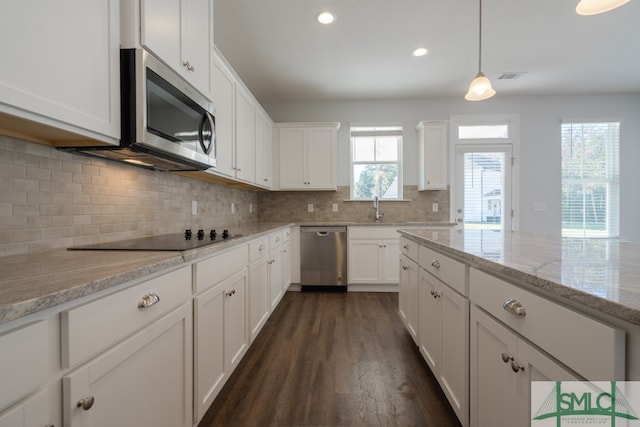 kitchen with light stone counters, stainless steel appliances, dark hardwood / wood-style floors, white cabinetry, and hanging light fixtures