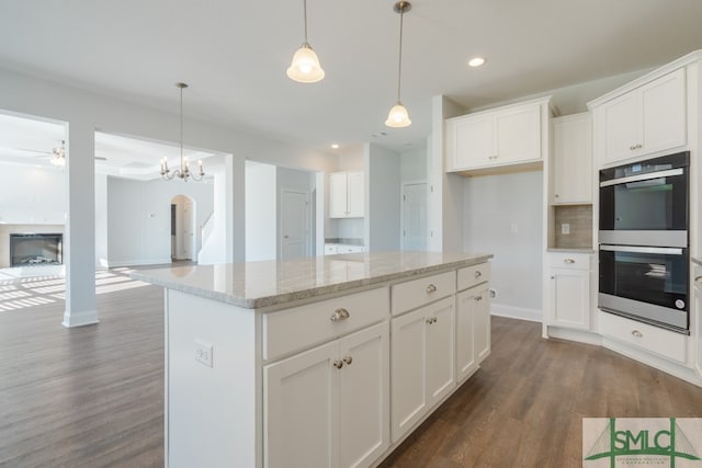 kitchen featuring double oven, dark hardwood / wood-style flooring, white cabinets, and hanging light fixtures