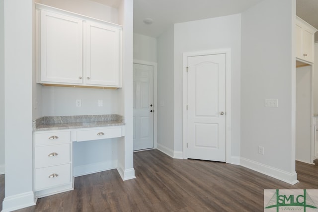 kitchen with built in desk, white cabinetry, and dark wood-type flooring