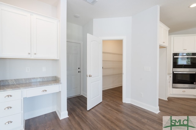 kitchen with dark hardwood / wood-style floors, built in desk, white cabinetry, and double oven