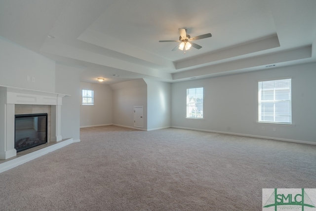 unfurnished living room featuring ceiling fan, a raised ceiling, and light colored carpet