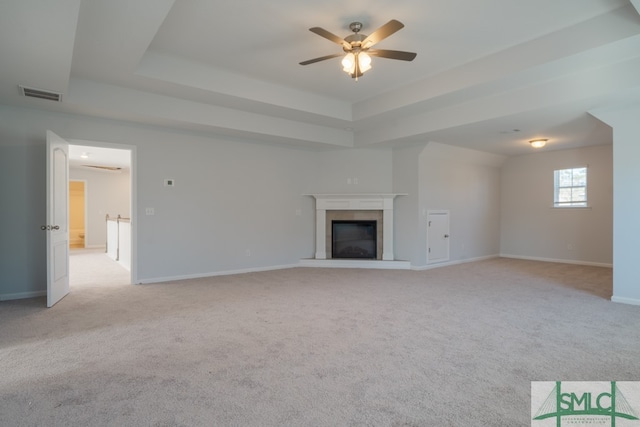 unfurnished living room with light colored carpet, a raised ceiling, and ceiling fan