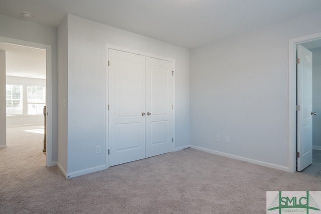 unfurnished bedroom featuring a closet and light colored carpet