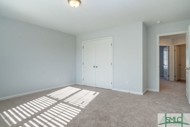 unfurnished bedroom featuring light colored carpet and a closet