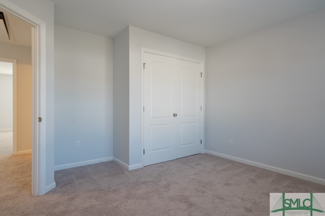 unfurnished bedroom featuring light carpet and a closet