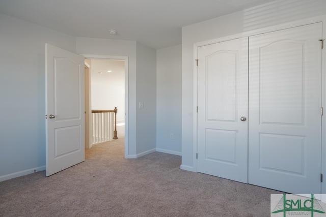 unfurnished bedroom with light carpet and a closet