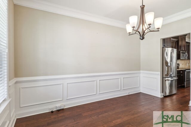 unfurnished dining area featuring crown molding, dark wood-type flooring, plenty of natural light, and a notable chandelier