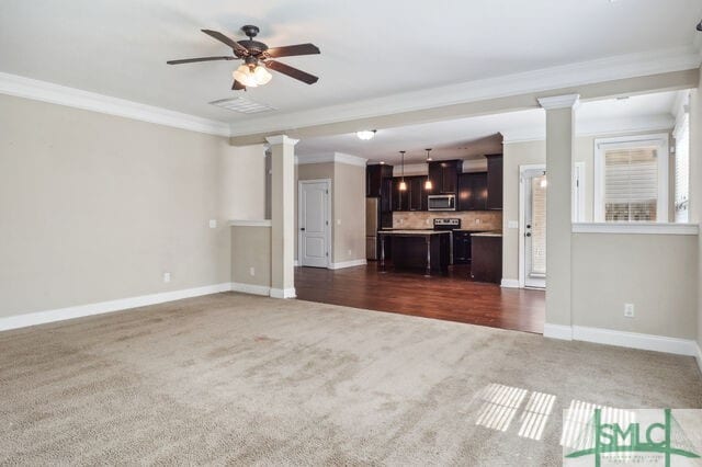 unfurnished living room with dark carpet, ornamental molding, ceiling fan, and decorative columns