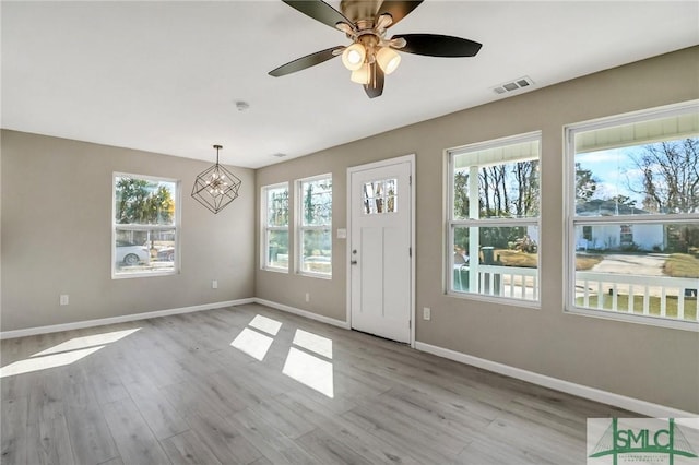 interior space featuring ceiling fan with notable chandelier and light hardwood / wood-style floors