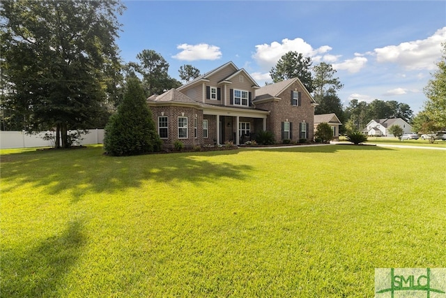 view of front of property with brick siding, a front lawn, and fence