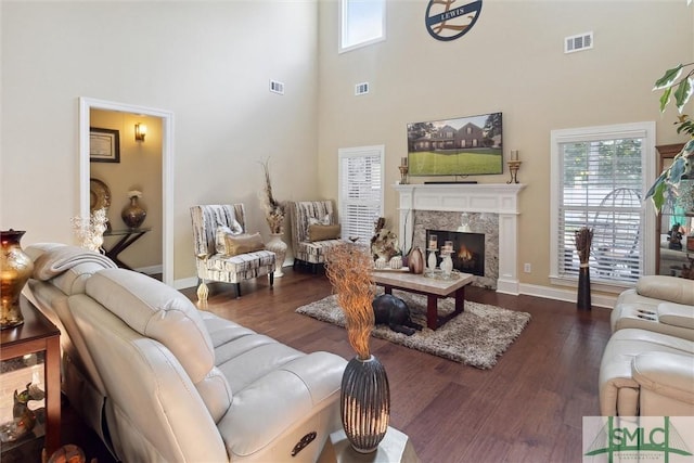 living room with dark wood-style floors, visible vents, and a premium fireplace