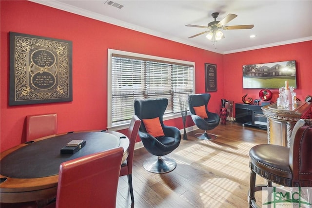 recreation room featuring ceiling fan, wood finished floors, visible vents, and crown molding