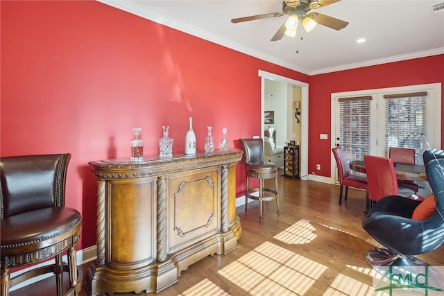 bar featuring ceiling fan, wood finished floors, visible vents, baseboards, and ornamental molding