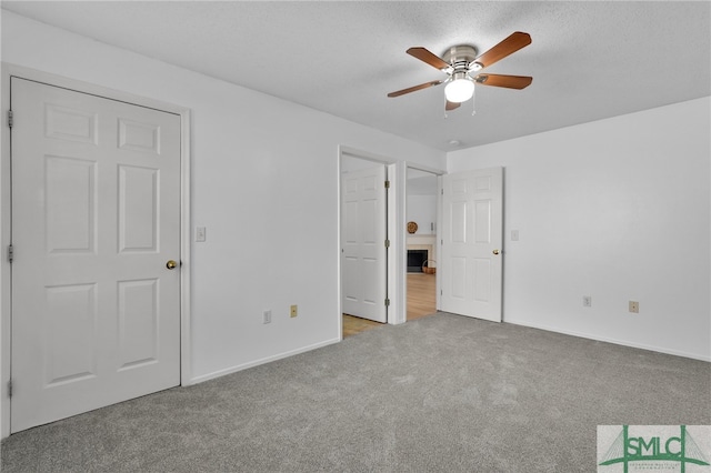 unfurnished bedroom with light colored carpet, a textured ceiling, and ceiling fan