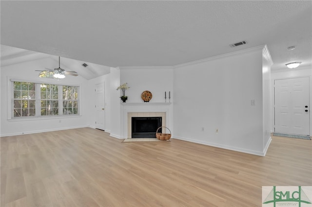 unfurnished living room featuring a tiled fireplace, light hardwood / wood-style floors, lofted ceiling, ceiling fan, and a textured ceiling