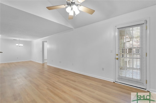 unfurnished room featuring ceiling fan with notable chandelier, vaulted ceiling, and light hardwood / wood-style flooring