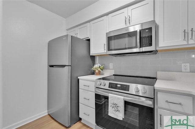 kitchen with light wood-type flooring, light stone countertops, stainless steel appliances, white cabinetry, and tasteful backsplash