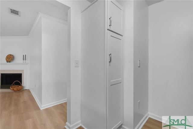 corridor featuring ornamental molding and light hardwood / wood-style flooring