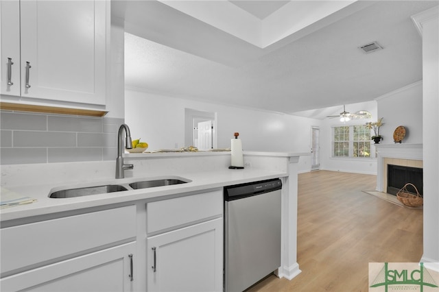 kitchen with white cabinetry, tasteful backsplash, dishwasher, sink, and light hardwood / wood-style floors