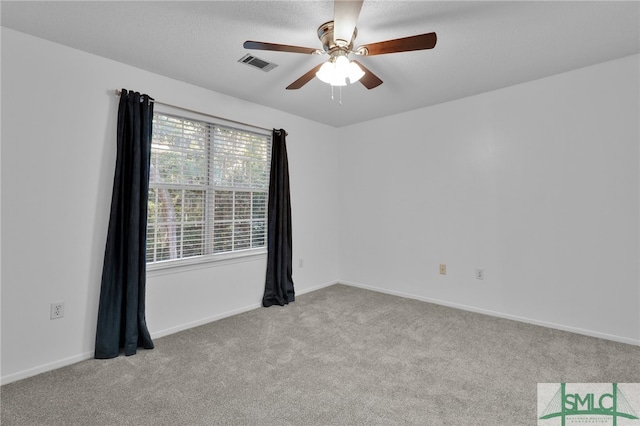 spare room featuring ceiling fan, light carpet, and a textured ceiling