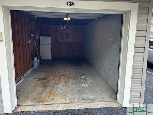 garage featuring white fridge and a garage door opener