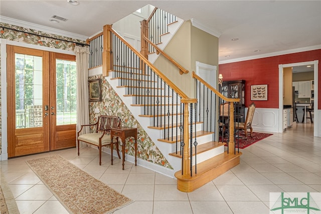 stairs with tile patterned flooring, a wainscoted wall, french doors, ornamental molding, and wallpapered walls