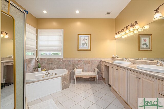 bathroom with tile patterned floors, tile walls, a relaxing tiled tub, and vanity