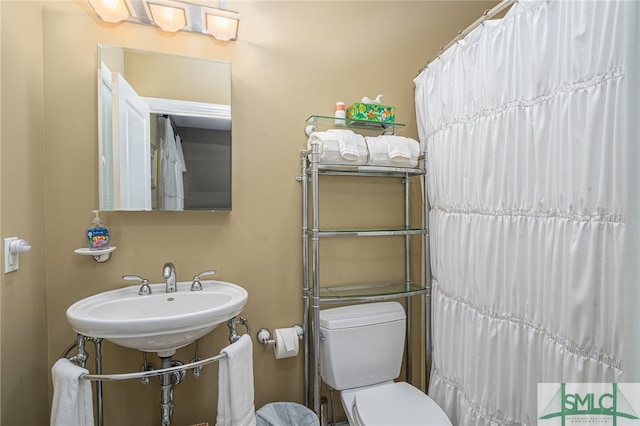 bathroom featuring a shower with curtain, a sink, and toilet